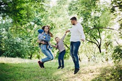 view active positive family having fun jumping park together with kids mother father embracing their