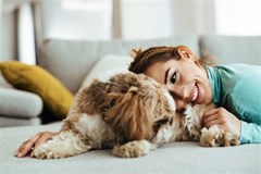 affectionate woman cuddling her dog while relaxing home